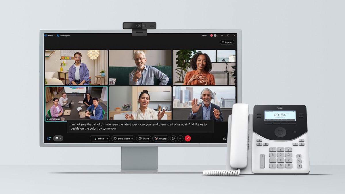 A monitor displaying a Webex conference call with a webcam on top and a Cisco desk phone.