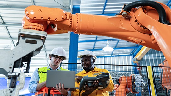Two manufacturing employees examine data on devices